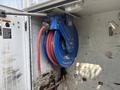 A blue hose reel mounted on a wall with red hoses coiled inside