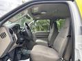 Interior view of a 2010 Ford F-550 Super Duty showing the driver's seat and passenger seat with light gray cloth upholstery and a dashboard with controls