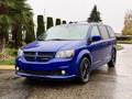 A blue 2020 Dodge Grand Caravan with a sleek design and black accents parked on a wet surface