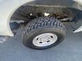 A close-up of a large off-road tire mounted on a wheel showcasing a rugged tread pattern and a shiny chrome rim