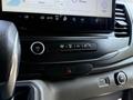 A close-up of the control panel in a 2022 Ford Transit featuring climate controls volume knob and hazard light button