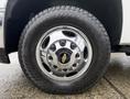 Front wheel of a 2013 Chevrolet Silverado 3500HD featuring a shiny chrome hubcap with a Chevrolet logo and a rugged tire tread pattern