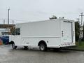 A white 2012 Ford Econoline van with a boxy design and a roll-up door at the back