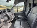 Interior view of a 2023 Ford Transit showing two black front seats and the dashboard with steering wheel and controls