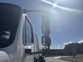 A 2022 Freightliner M2 106 truck with a prominent side mirror reflecting light and showing the vehicle's sleek design and sturdy build