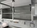 Interior of a 2020 Freightliner MT45 with metal shelving units mounted above a work surface and electrical outlets on the wall