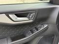 A close-up view of the door panel of a 2020 Ford Escape featuring door controls for windows and locks with a textured design around the handle