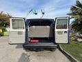 A blue 2013 Ford E-350 Super Duty van with open rear doors revealing a spacious interior and a folded rear bench seat