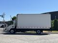 A 2022 Isuzu NQR truck with a large white box cargo area and a cab painted in light colors positioned on a paved surface