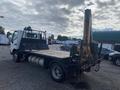 A 2019 Hino 195 flatbed truck with a mounted crane at the rear parked on a gravel surface