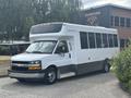 A 2020 Chevrolet Express shuttle bus with a white exterior and large windows designed for passenger transport