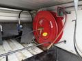 A red hose reel mounted inside a truck bed with a hose attached ready for use