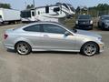 A silver 2013 Mercedes-Benz C-Class coupe is parked side-on showing its sleek profile and sporty design