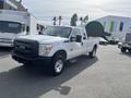 A 2014 Ford F-250 SD in white with a black grille and chrome wheels parked in a lot
