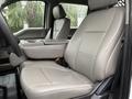 Two spacious beige leather front seats of a 2022 Ford F-550 with a built-in armrest between them