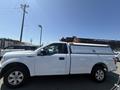 A white 2019 Ford F-150 with a truck cap on the bed parked with its side facing the viewer
