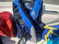 A blue and black life jacket designed for water activities with straps and safety features displayed on a boat seat
