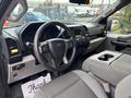 Interior view of a 2020 Ford F-150 featuring a black steering wheel a dashboard with gauges and controls and gray fabric seats