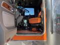 The interior cabin of a 2009 Peterbilt Highway truck featuring orange seats a steering wheel and controls visible from the open door