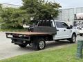 A 2019 Ford F-350 SD with a flatbed is parked on the grass showing its chrome wheels and a black rear cargo area