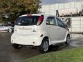 A white 2012 Mitsubishi I-MiEV is featured with a compact design and a rounded rear end showcasing distinctive tail lights and wheels
