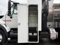 A 2011 International 7500 truck features an open storage compartment with a black floor and steps visible inside