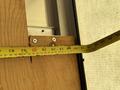 A measuring tape is extended against a wooden board showing measurements in inches and centimeters