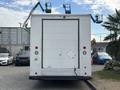 A white 2018 Ford Econoline van with a closed rear door and two elevated work platforms mounted on the roof
