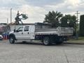 A 2014 Ford F-550 pickup truck with a flatbed trailer in the rear parked on a street