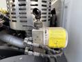 A close-up of a mechanical component featuring a yellow label connected to hoses with a valve and a metal casing on a 2010 Autocar Xpeditor engine