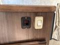 A control panel featuring a red circuit breaker switch labeled Atwood and a beige toggle switch mounted on a wooden surface
