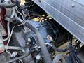 Close-up of the engine components of a 2014 Hino 195 featuring various hoses wires and metal parts with a focus on the transmission assembly