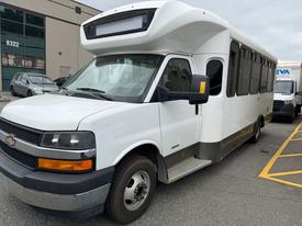A white 2017 Chevrolet Express with a raised roof and large windows parked at a facility