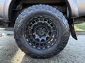 A black tire mounted on a 2004 Toyota Tacoma with a rugged tread pattern and a black alloy wheel