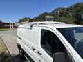 A 2016 Ford Transit van with a white exterior and a roof rack featuring several mounts for carrying equipment