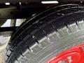 A close-up of a treaded tire on a red wheel from a 2001 Toyota Dyna showing detailed patterns and water droplets on the surface