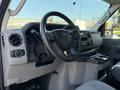 Interior view of a 2021 Ford Econoline showing steering wheel dashboard and front seat with cup holders and control panel