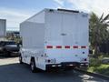 A white 2012 Ford Econoline E-450 box truck with a rear door and reflective red stripes on the back panel