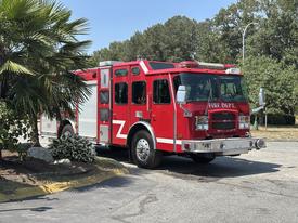 A red 2006 E-One Typhoon fire truck with multiple windows and emergency lights parked on a road