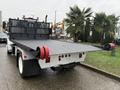 A 2019 Freightliner M2 flatbed truck featuring a textured black loading surface and red rollers on the edges