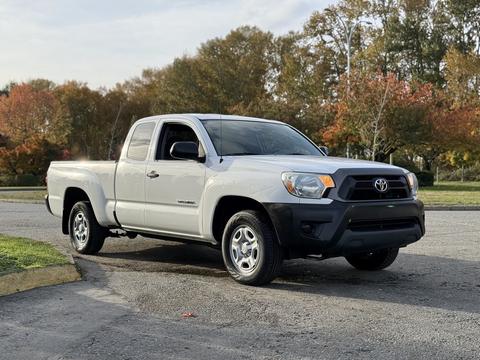 A silver 2013 Toyota Tacoma pickup truck with a black front grille and silver wheels parked on a paved surface