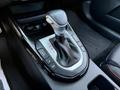 The gear shift of a 2024 Kia Forte5 featuring a black leather boot and several buttons for driving modes and settings