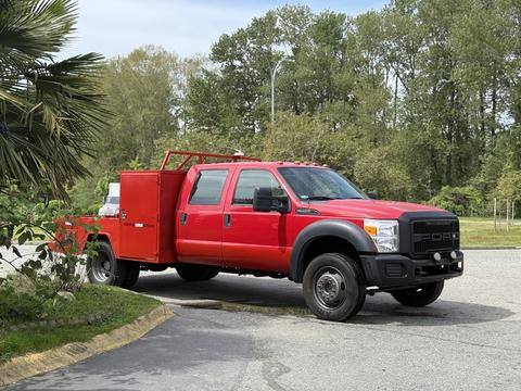 A red 2013 Ford F-550 with a tool compartment in the truck bed parked at an angle with visible front grille and cab