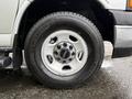 Close-up of a tire and wheel of a 2023 GMC Savana featuring a silver rim and a black tire with rugged tread pattern