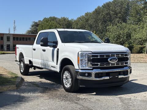 A white 2023 Ford F-350 Super Duty truck with a chrome grille and large wheels parked facing slightly to the right