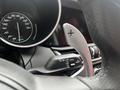Close-up of the gear shift paddle on a 2023 Alfa Romeo Giulia with a speedometer visible in the background