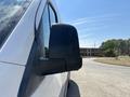 A close-up of the side mirror of a 2019 Mercedes-Benz Sprinter showing a black mirror housing and part of the vehicle's white body