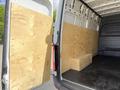 A 2022 Mercedes-Benz Sprinter van with wooden panels installed on the sides of the cargo area and a wooden box placed on the floor inside the van