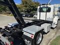 A 2020 Peterbilt 330 truck with a flatbed and visible hydraulic lift system showcasing its robust design and metallic finish