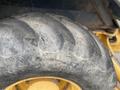 Close-up of a large, worn tire from a 2012 John Deere 310SJ vehicle showing distinct treads and a rugged surface